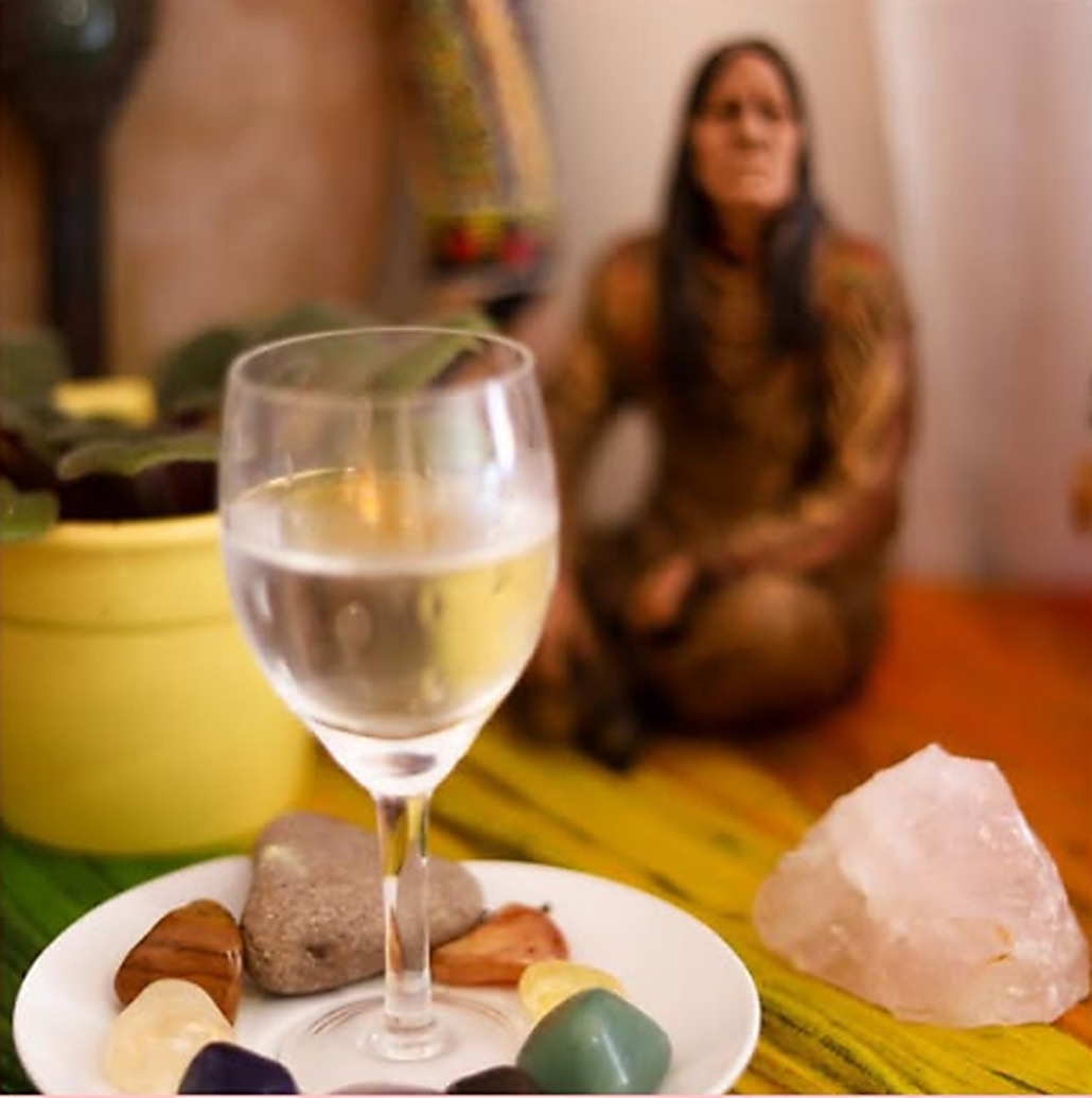 Mesa com cristais, pedras e um cálice de água durante um atendimento energético