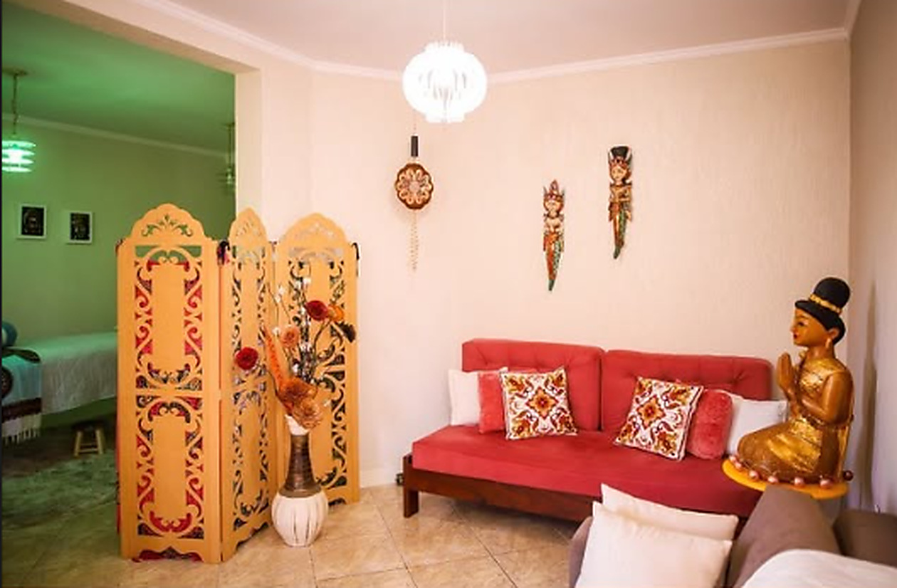Sala de espera do Espaço Sonho e Luz com sofá vermelho, biombo entalhado e estátua dourada