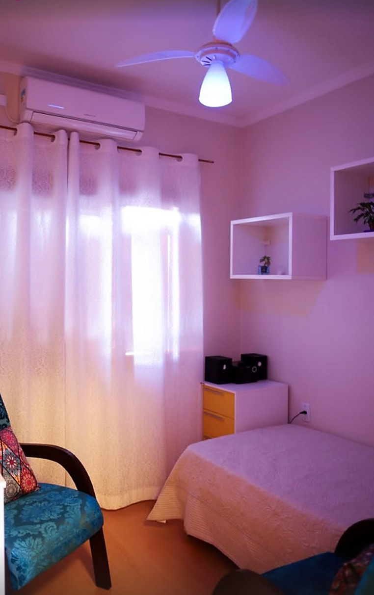 Quarto de atendimento com luz suave, cortina clara e poltrona estampada
