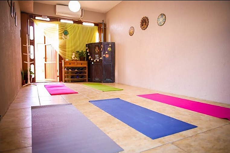 Sala ampla do espaço com tapetes coloridos dispostos no chão para vivências em grupo